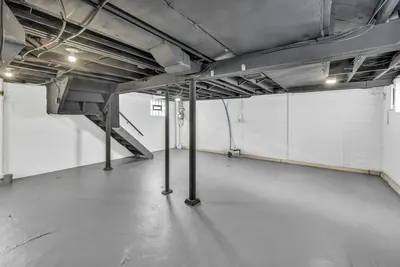 Unfinished basement with steel columns, stairs and a gray painted floor